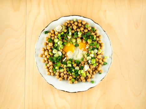 Chickpeas with fried eggs and fresh onion on plate