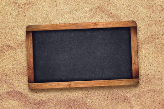Blank chalkboard slate in desert sand, top view
