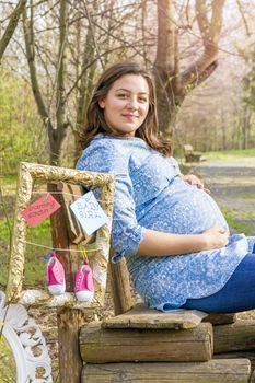beautiful pregnant woman outdoor in the park on banch