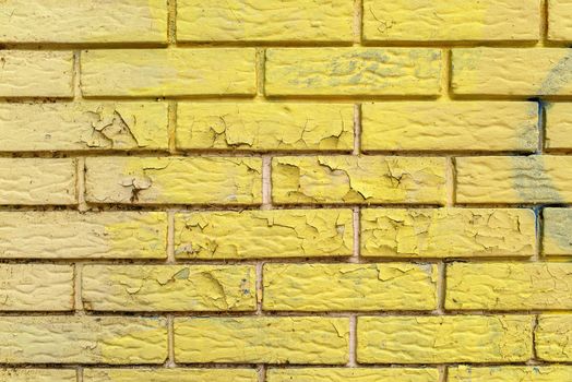 Yellow paint peeling of brick wall masonry surface