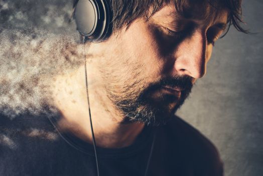 Male DJ listening to music on headphones with eyes closed