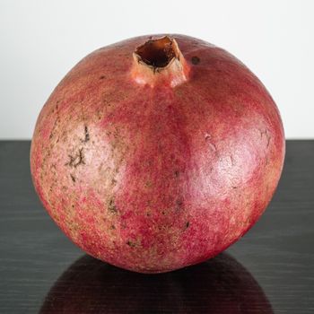  half ripe pomegranate fruit isolated on black wooden plane and white background 
