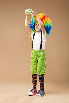 Full-length portrait of Happy clown boy with large colorful wig.
