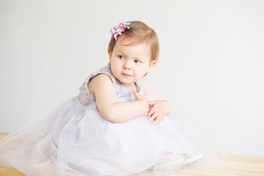 Portrait of a lovely little girl wearing elegant gray dress in front of a white background. Little princess