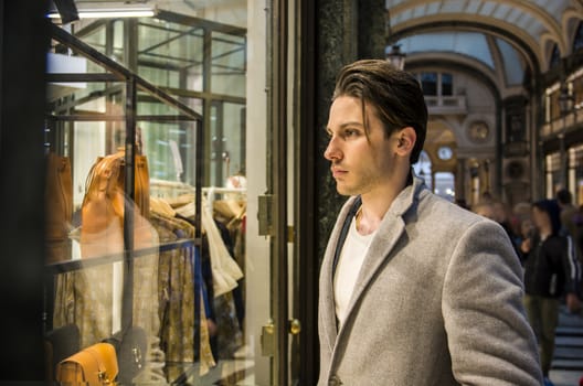 Handsome Young Man in Black Elegant Suit Looking at Displayed Fashion Items in Glass Window Boutique at the High Street Side.