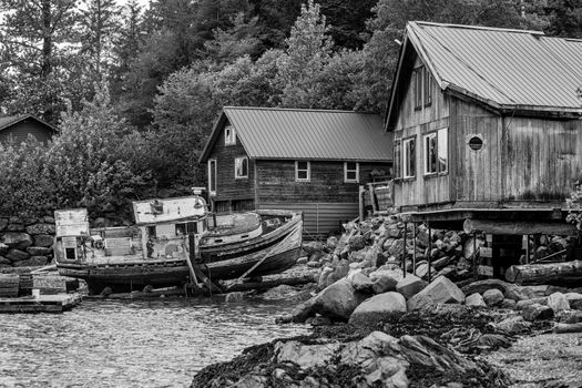 Black and white waterfront buildings and an abandoned boat near Ketchikan in Alaska