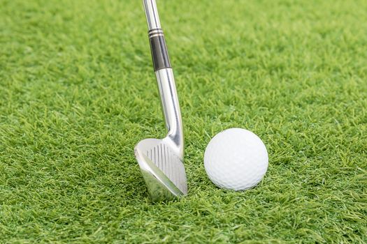 Golf ball and golf club on green grass