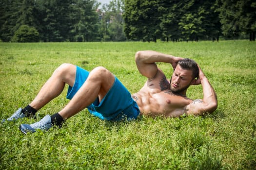 Bearded sportsman doing abs exercise in park