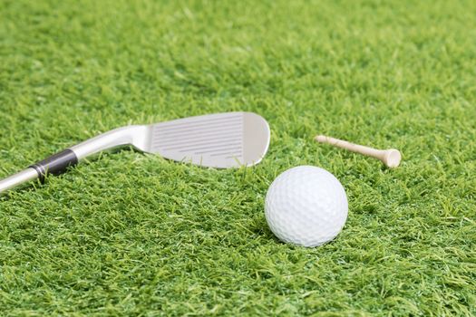 Golf ball and golf club on green grass