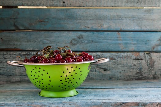 cherries in a colander on a wooden background