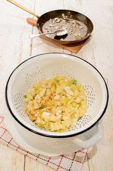 fried white cabbage and spring onions in a colander