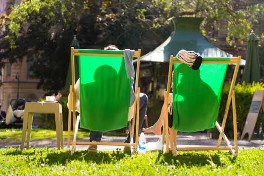 Silhouette of relaxed couple on deckchairs in a park