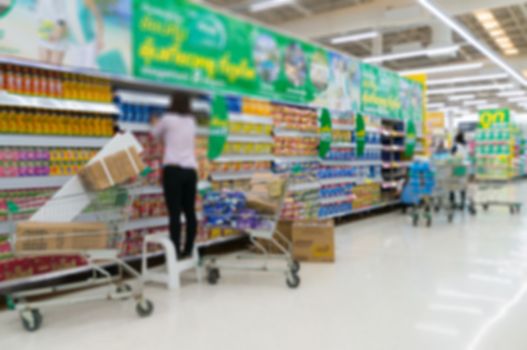 Merchandising. Sales assistant in supermarket arrange goods on s