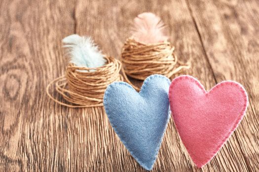 Love, Valentines Day. Hearts couple Handmade and nests with feathers on wooden background. Vintage retro romantic style. Vivid unusual creative greeting card, multicolored felt. Grain effect, toned