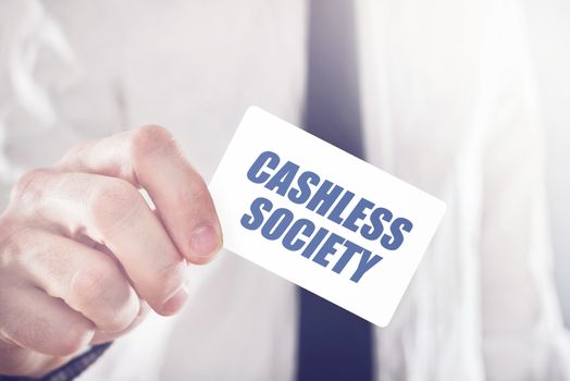 Businessman holding card with Cashless society title