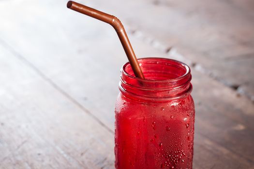 Iced drink in red glass on wooden table