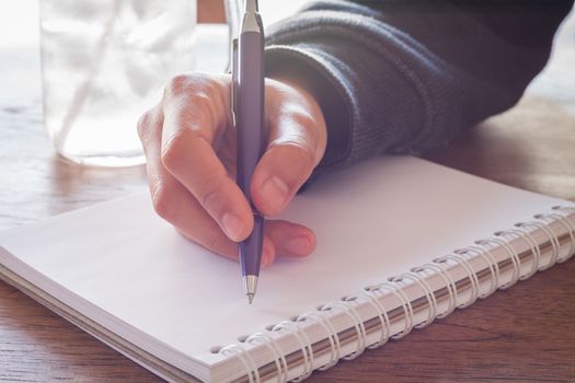 Woman hand with pen writing on notebook