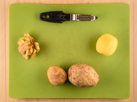 Potatoes and skins on green plastic board