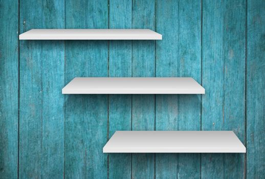 Three white shelves on blue wooden texture background