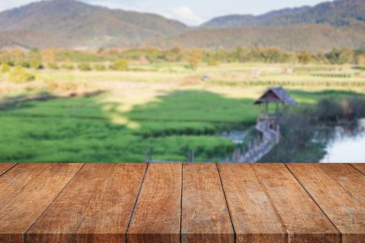 Perspective top wooden with green rice field blurred background