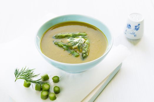 Asparagus soup in a bowl with fresh cream, dill and chive