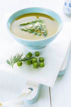 Asparagus soup in a bowl topped with fresh cream, dill and chive