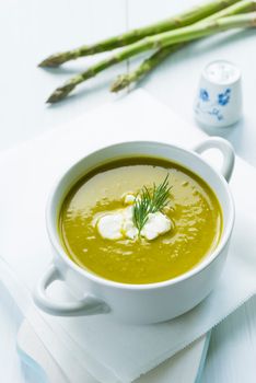 Bowl of asparagus soup topped with fresh cream and dill