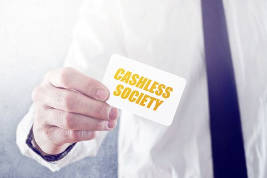 Businessman holding card with Cashless society title