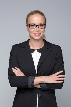 Business woman standing with arms crossed against gray background..