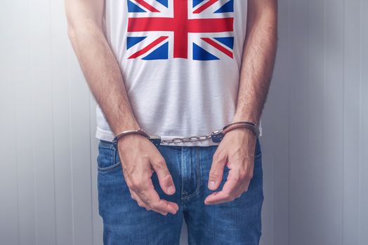 Arrested man with cuffed hands wearing shirt with UK flag