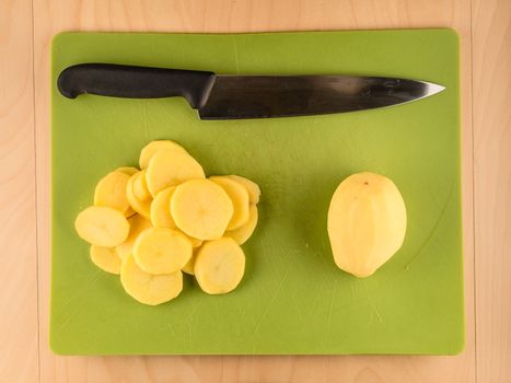 Sliced potatoes and knife on green plastic board