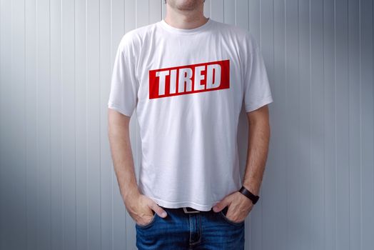 Guy wearing white t-shirt with label Tired printed on chest