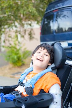 Handsome biracial disabled boy in wheelchair, smiling outdoor, r
