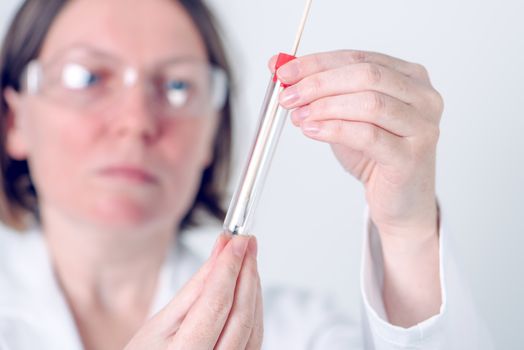 Female laboratory specialist holding test tube with cotton swab