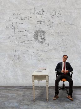 man sitting on desk and physic formula on wall