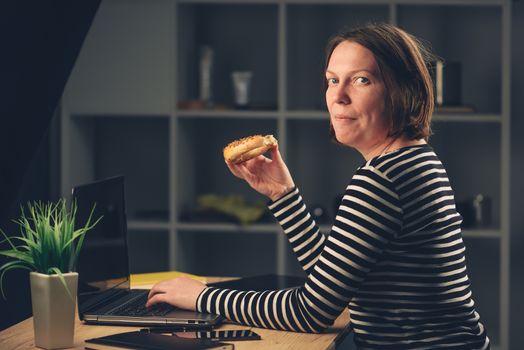 Woman eating sesame bagel in office