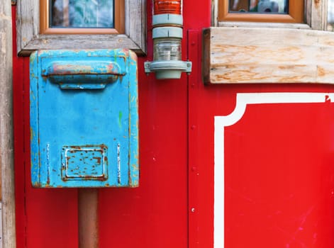 old blue mailbox hanging on red wall