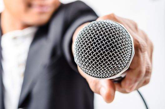 Businessman making speech with microphone and hand gesturing.