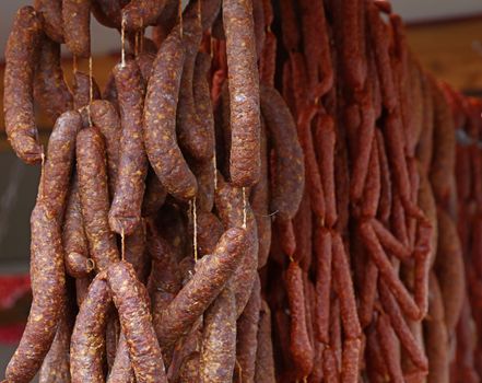 Cured smoked red meat sausages hanging in store