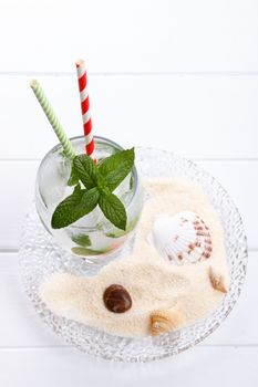 Refreshing summer drink, fizzy water with ice and mint on white wooden board. 