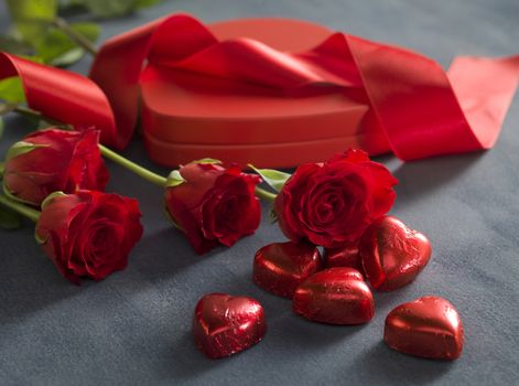 red hearts chocolates in front of red roses and hart shaped box