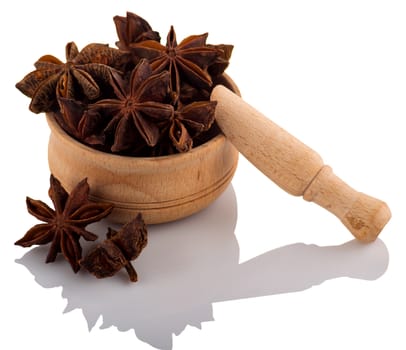 Star anise in a wooden bowl on a white background.