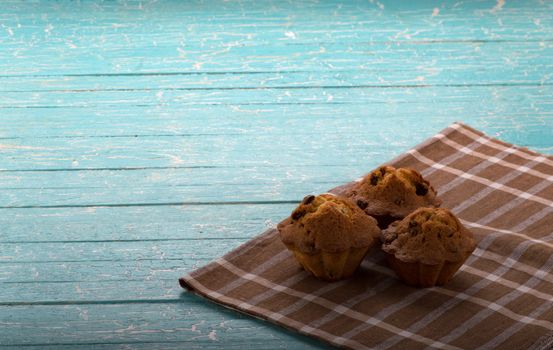 Muffins with raisins on a checkered napkin on a blue background