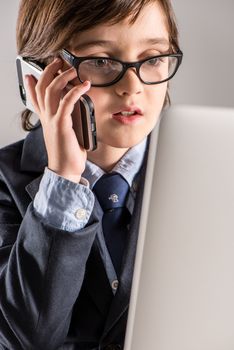 Schoolchild in business suit talking on smartphone