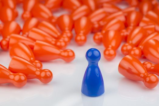 Conceptual orange game pawns and a blue play pawn as abstract display of inequality in color and number of
