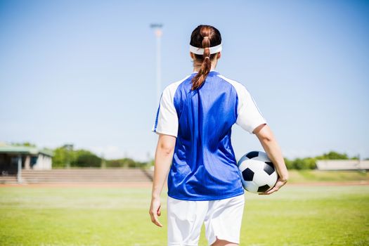 Rear view of soccer player standing with a ball