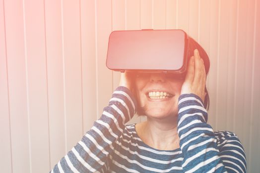 Woman watching 360 video with virtual reality headset. Female using VR goggles to enjoy futuristic multimedia content that simulates physical presence and allows interaction with environment.