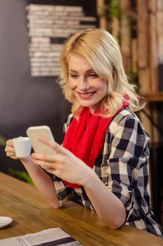 Woman drinking coffee and using smartphone