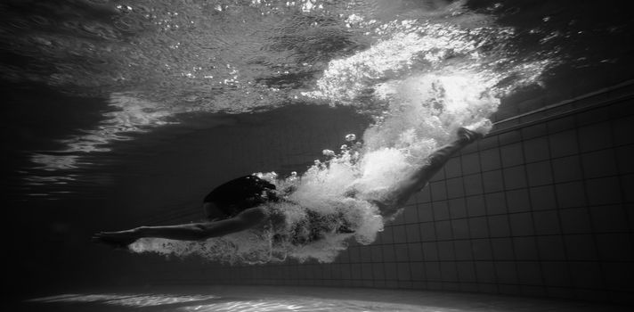Athletic swimmer smiling at camera underwater