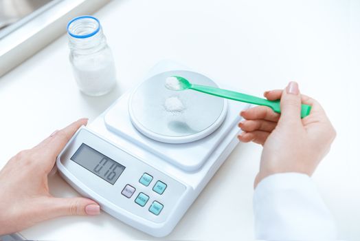 Close-up partial view of chemist weighing reagent on laboratory scales